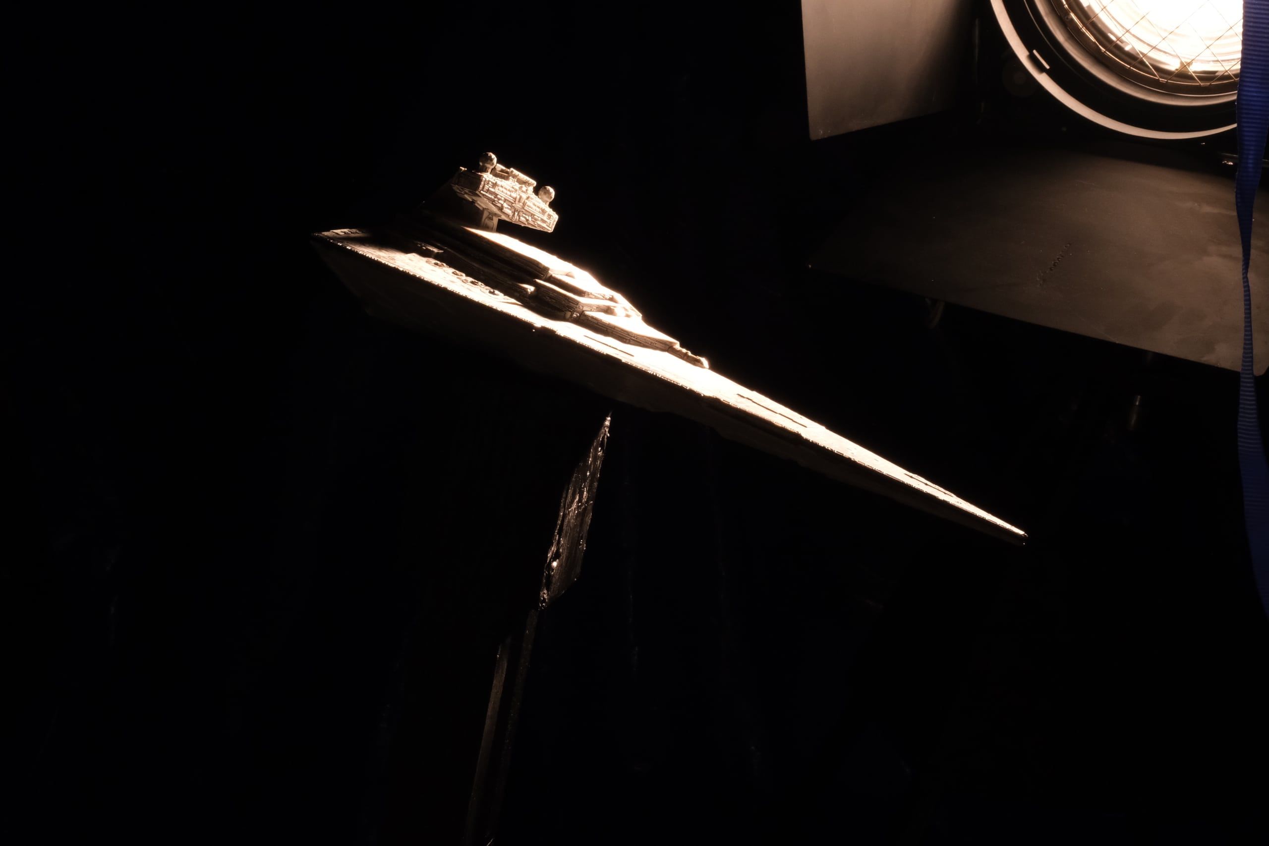 The starship miniature in front of a fresnel lamp in the dark workshop.