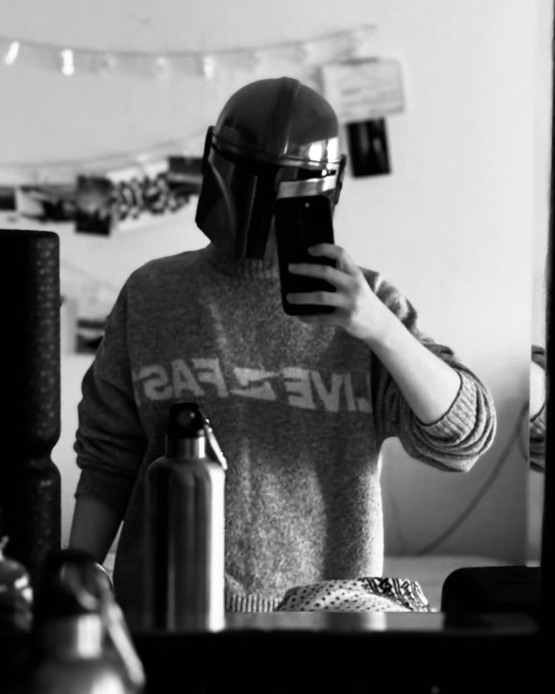 Andi in a mirror portrait wearing a Mandalorian helmet